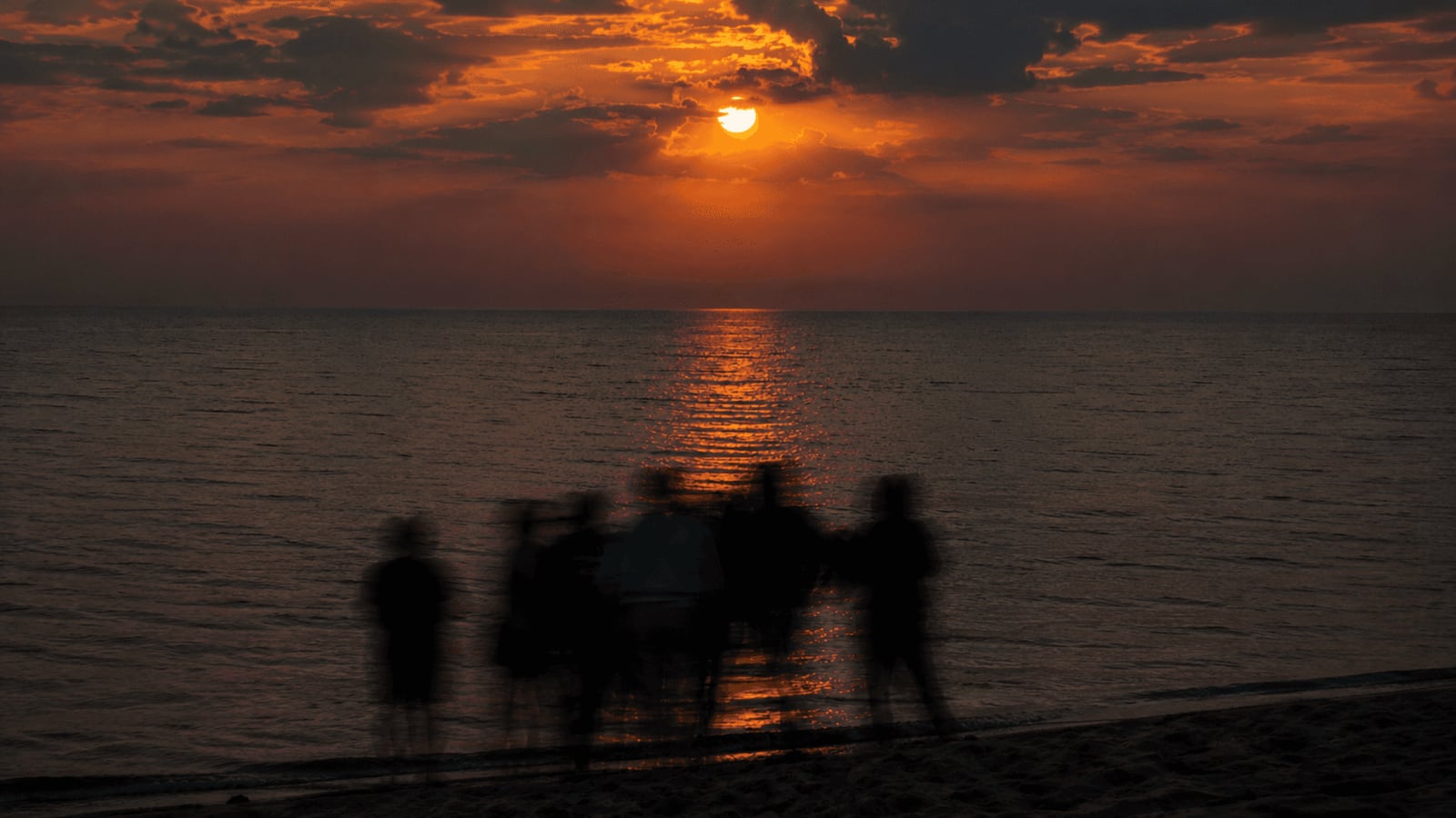 Friends gathered on a beach at sunset